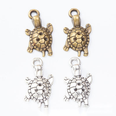 Product view of turtle charm showing a small turtle with four feet, a patterned round shell, and a top loop