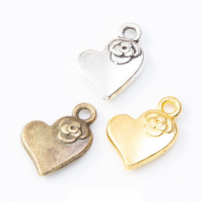 Heart-shaped charm topped with a rose shown across the available finishes
