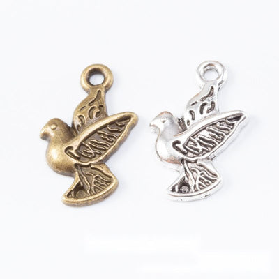 Product view of peace dove charm showing a side-view dove carrying an olive branch with engraved wing details and a top 