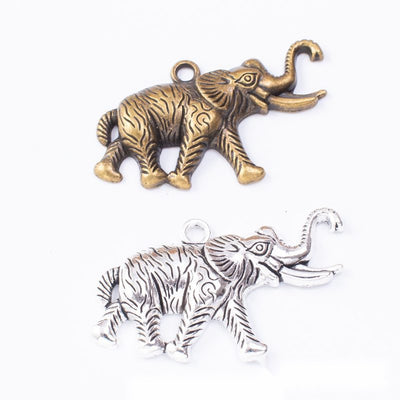 Walking elephant charms with raised trunks and textured blankets arranged together on a white background.