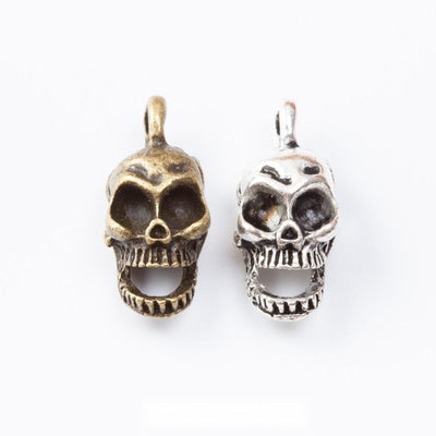 Grouped front view of skull charm showing deep eye sockets and a toothy open mouth