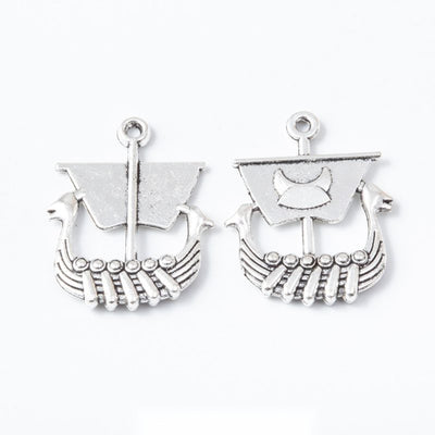 Product view of Viking longship charm showing a Viking-style longship with a square sail, curved hull, rows of oars, and