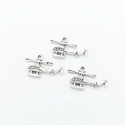 Small silver-tone airplane charms arranged on a pale background