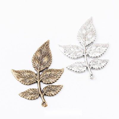 Five Leaf Branch Charm Pendant finish comparison showing five textured leaves arranged along a slim stem