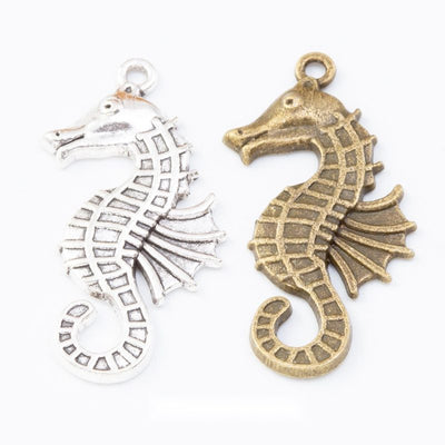 Curled seahorse charms with segmented bodies and ridged fins arranged together on a white background.