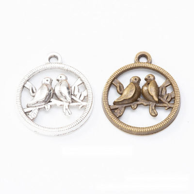 round lovebird openwork metal charms in two finishes shown together in the available finishes