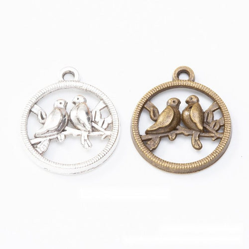 round lovebird openwork metal charms in two finishes shown together in the available finishes