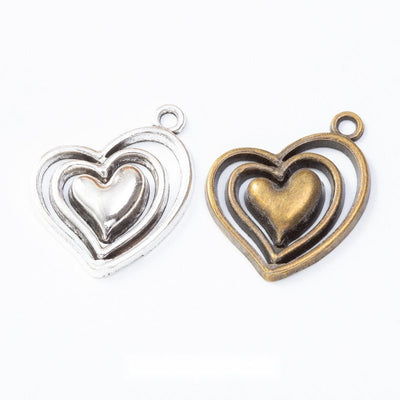 Grouped front views of the layered open heart metal charm in two antique finishes