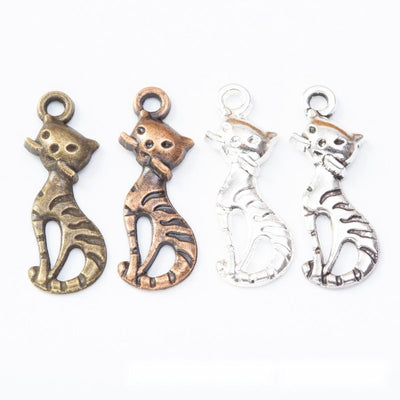 Grouped front views of the striped sitting cat metal charm in four metallic finishes