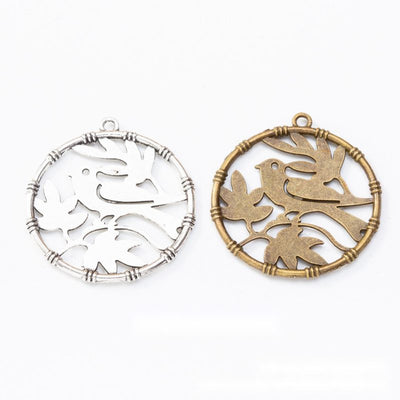 Product view of bird cutout charm showing a round frame filled with overlapping flying bird silhouettes and a top loop