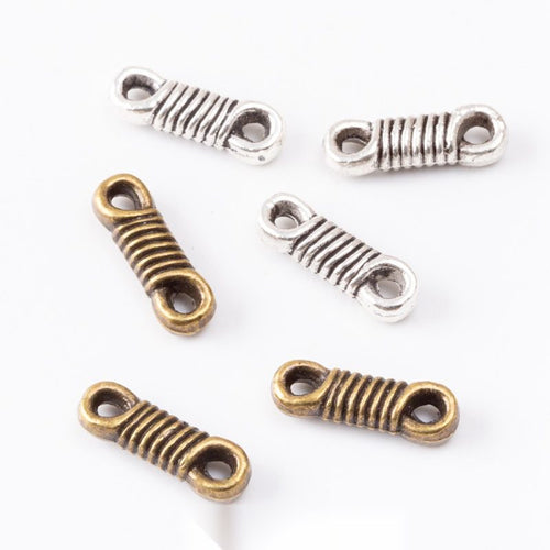 Assorted antique bronze and antique silver small wrapped coil double loop connector pieces on white