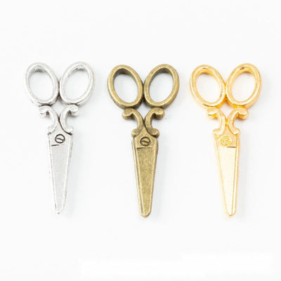 Grouped front view of scissors charm showing outlined handles and slim blades