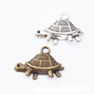 Side-view turtle charms with domed textured shells arranged together on a white background.