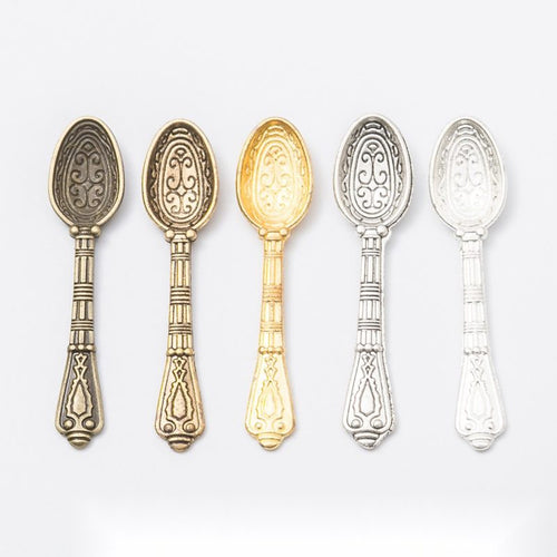 Overview of long ornate spoon charm pieces on a white background