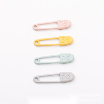 Slender safety pin with a rounded numbered cover shown in the available finishes