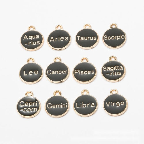 Product view of zodiac charm assortment showing round black enamel discs labeled with the twelve zodiac signs in pale le