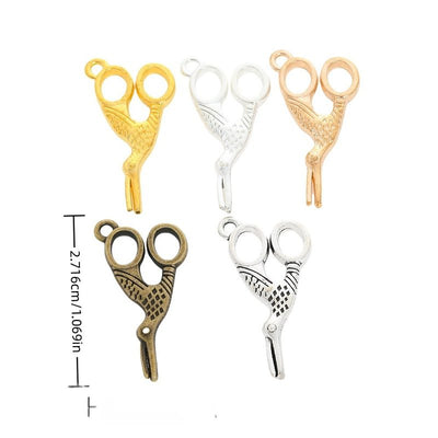 Small scissors-shaped charms with finger loops and textured blades arranged together on a white background.