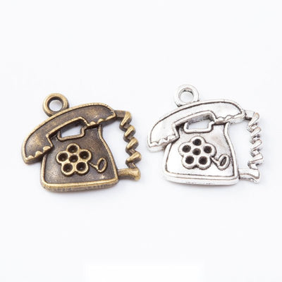 Vintage telephone charms with raised rotary dial details arranged together on a white background.