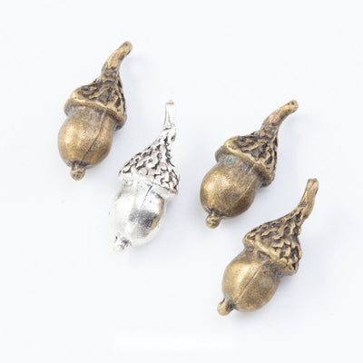 Assorted textured acorn charms arranged together on a white background