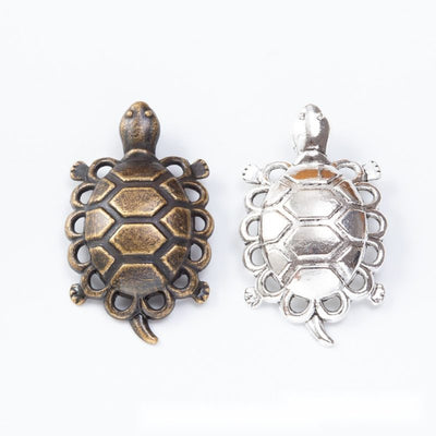 Turtle-shaped bezel charms with open lattice shell borders arranged together on a white background.