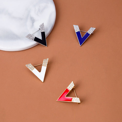 Black blue white red V brooches arranged on marble and brown
