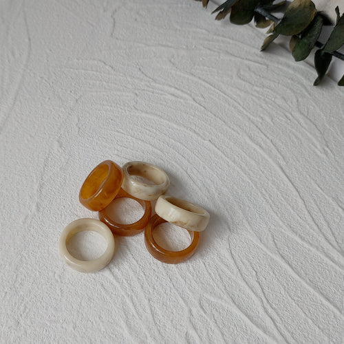 Cream-white and amber-brown chunky round-band rings showing the mixed ring group.