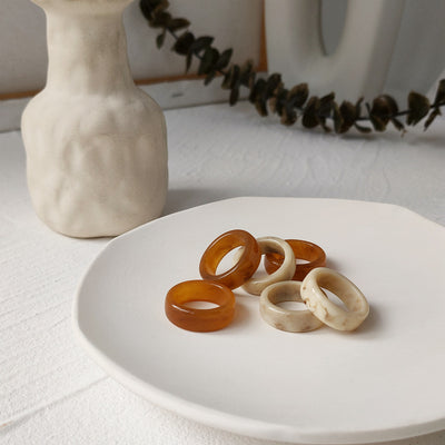 Cream-white and amber-brown chunky round-band rings showing both colors.