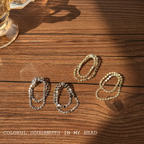 Silver and gold double disc loop stud pairs on wood table