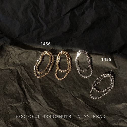 Gold 1456 and silver 1455 double disc loop studs on black cloth