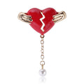 Hands Holding Broken Red Heart Brooch With Pearl Drop view 1
