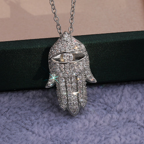 Silver Hamsa pendant close-up against green box edge