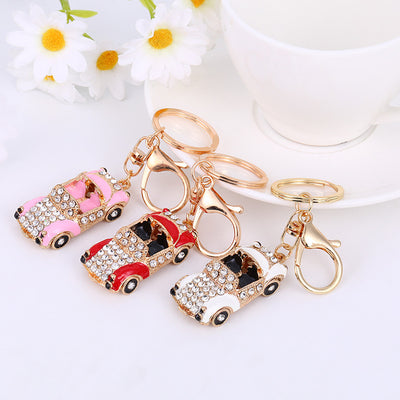 Three rhinestone convertible car keychains in pink, red, and white