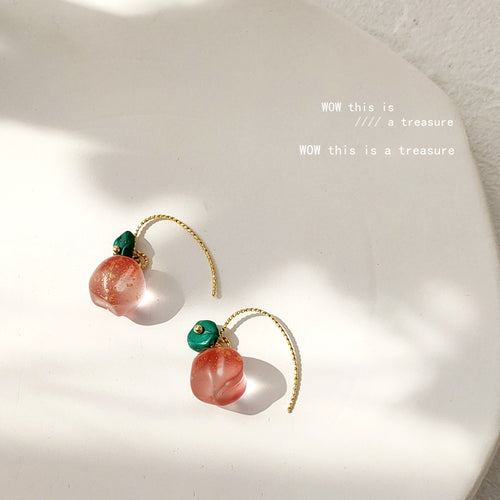 Pink peach resin drop earrings on white ceramic plate