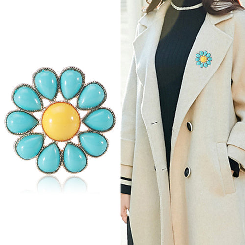 Angled display of the turquoise enamel daisy brooch with yellow round center
