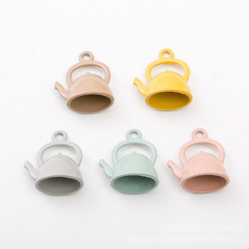 Close front view showing the shape and recessed details of the pastel teapot charms