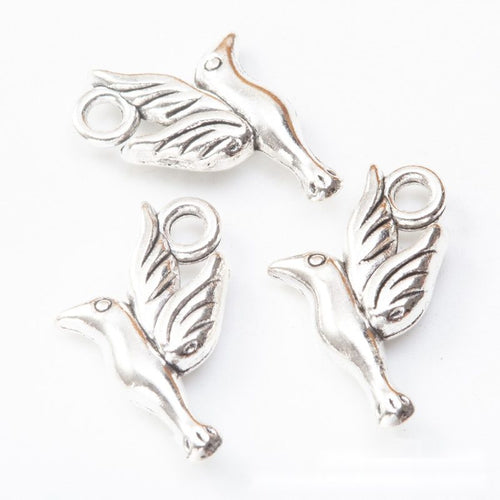 Close product view of the bird and leaf pendant charm in two antique metal finishes