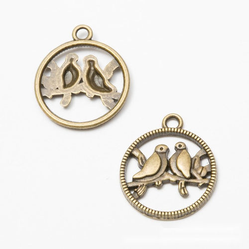 Front and reverse views of the round lovebird openwork metal charms in two finishes