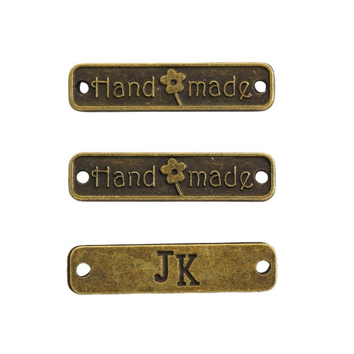 Close front view of handmade tag showing embossed lettering, a flower motif, and two holes