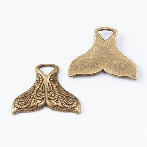 Whale-tail charms with engraved swirling linework shown from the front on a white background.