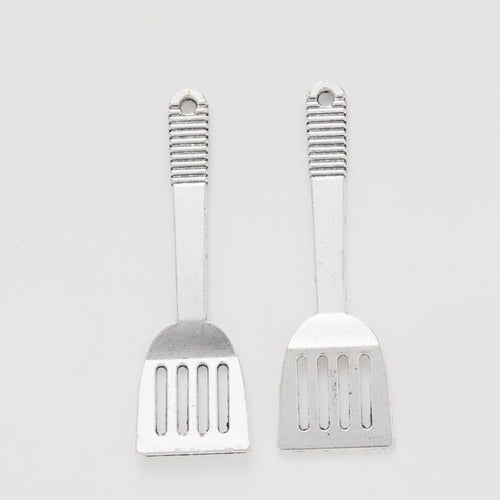 Front and reverse views of the silver-tone slotted spatula charm