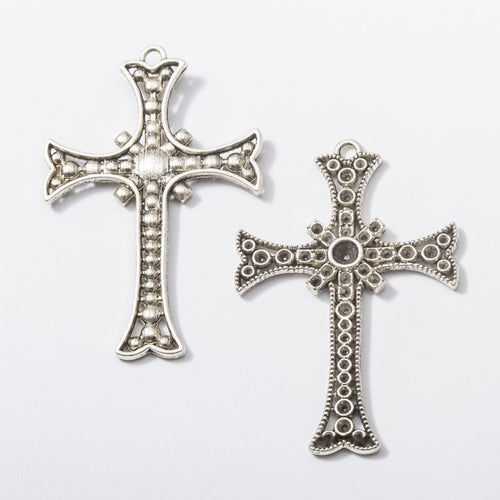 Close view of the a flared cross silhouette edged with dotted and scroll-like relief