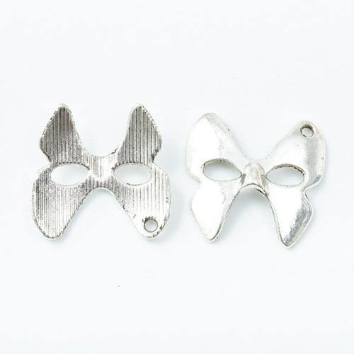 Close product view of the bow masquerade mask metal charm in two antique finishes