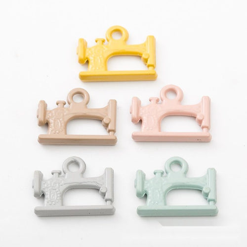 Mini sewing machine charms with smooth pastel coatings shown from the front on a white background.