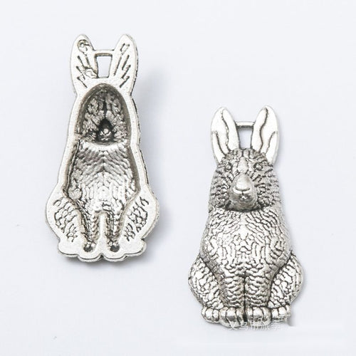 Front and reverse details of sitting rabbit charms on a white background