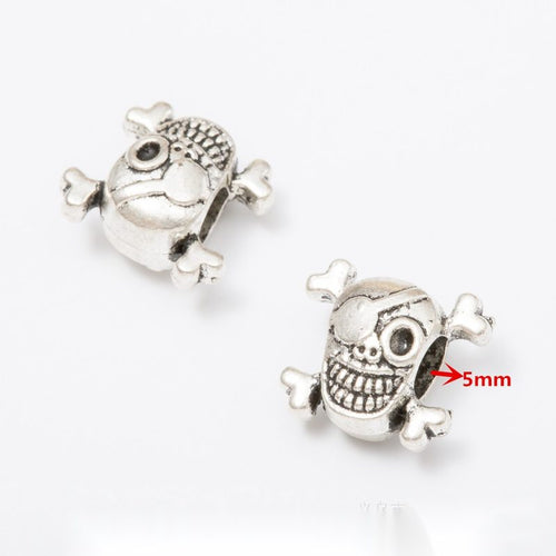 Front and reverse details of skull and object beads on a white background