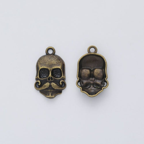 Front and reverse views of the sculpted skull head metal charms in two antique finishes