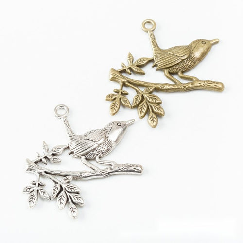 Bird on Branch Metal Charm Pendants shown in a angled detail view on a plain background