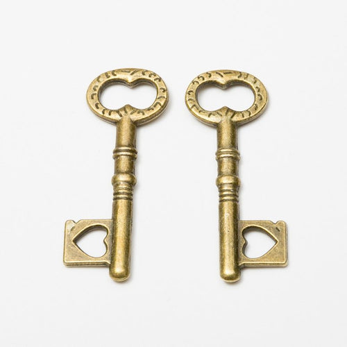 Close product view of the heart bow skeleton key charm in seven metallic finishes