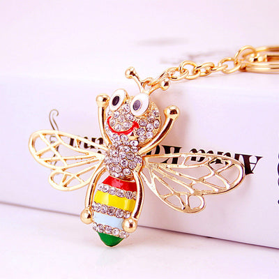 Close-up of a smiling gold-tone bee charm with clear stones and multicolored body stripes.