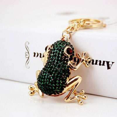 Angled view of a dark green rhinestone frog attached to gold-tone keychain hardware.
